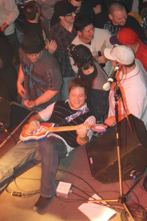 Un guitariste de Turbo Distortion penché vers le public pendant un spectacle